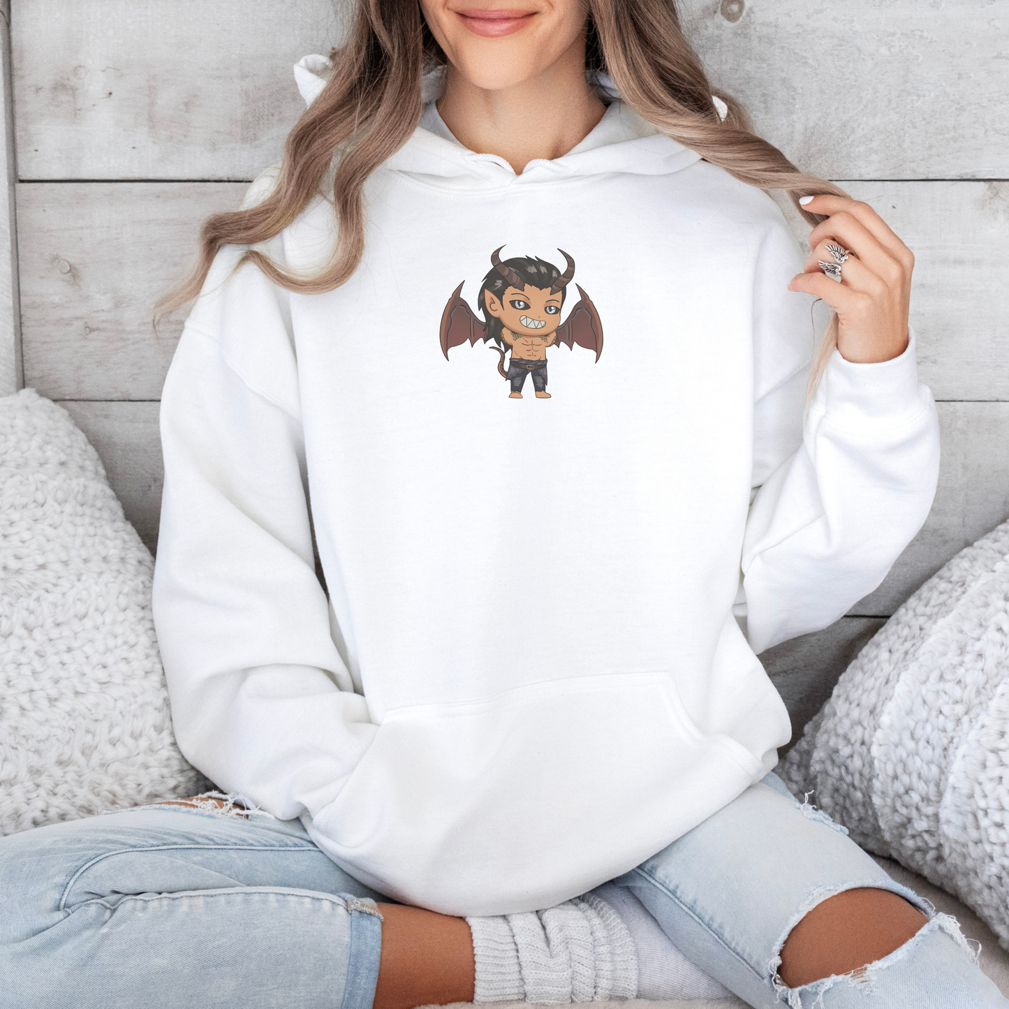 Person wearing a white hoodie with a cartoon character design, sitting on a wooden floor.