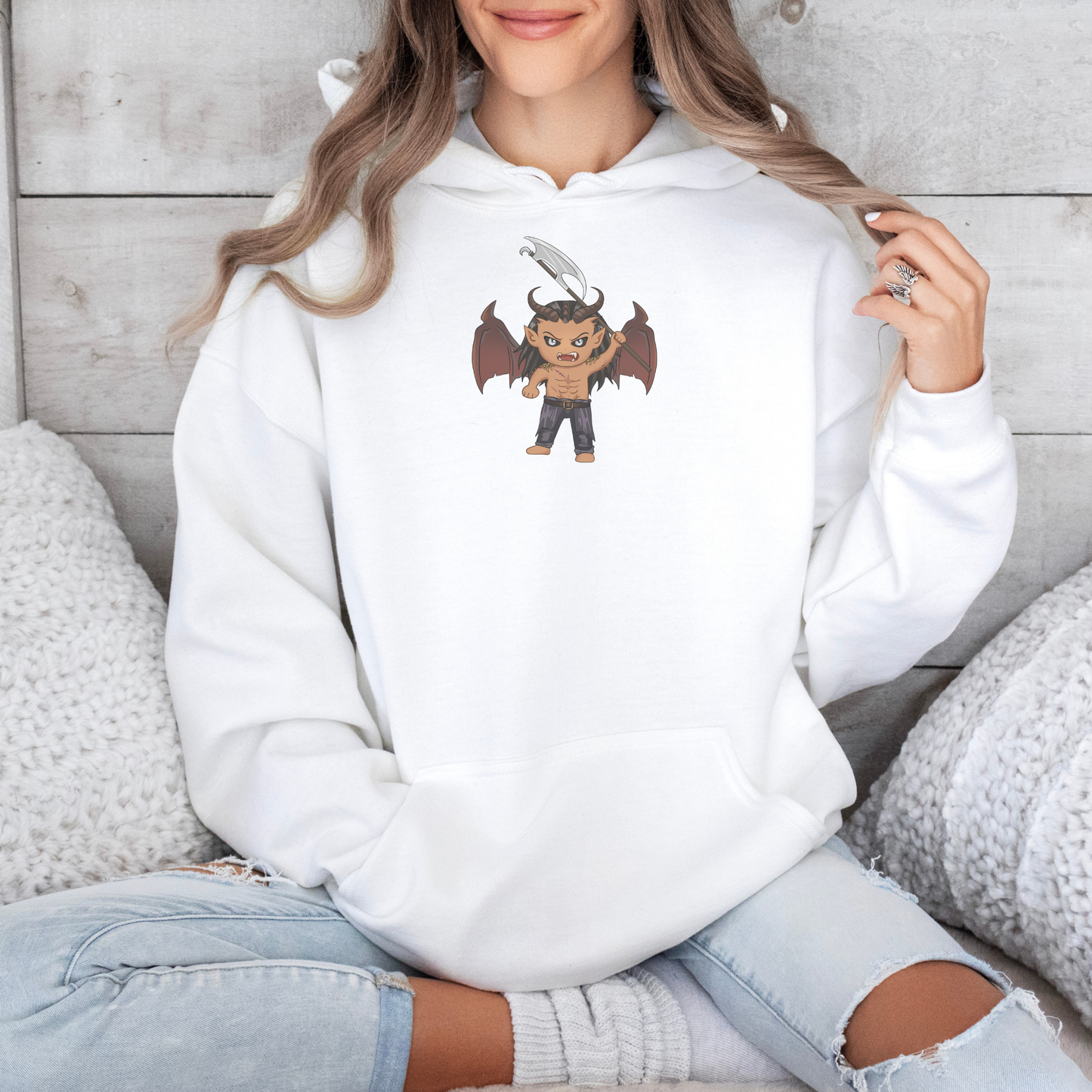 Person wearing a white hoodie with a cartoon character design, sitting on a wooden floor.