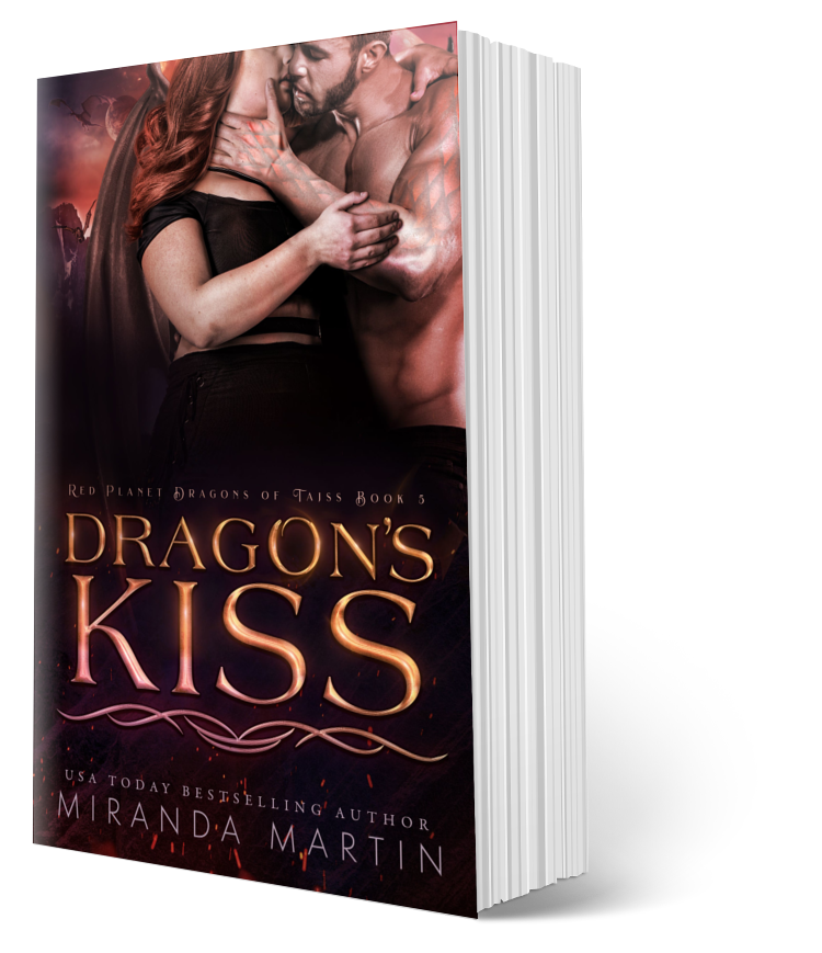 This image displays the paperback version of the book titled "Dragon's Kiss" by Miranda Martin, the fifth book in the Red Planet Dragons of Tajss series. The cover features an intense and romantic scene with the main characters, a human woman and an alien dragon-man, embracing closely in a setting that hints at the book's sci-fi and fantasy elements.