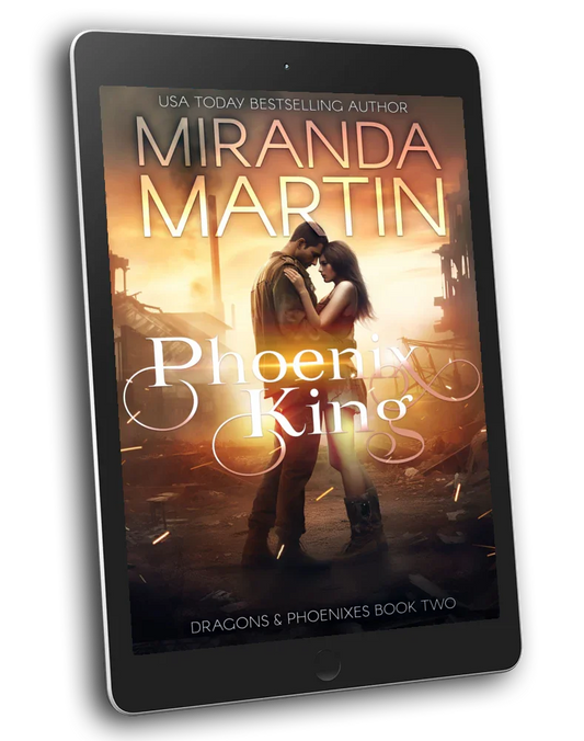 A digital tablet displaying the cover of the book 'Phoenix King' by Manda Mabro, featuring a man and a woman with a dramatic background.