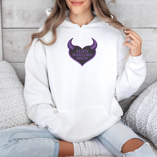 Person wearing a white hoodie with 'Alien Warlord Bride' design, sitting on a wooden floor.