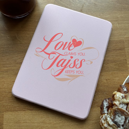 Pink notebook with 'Love Claims You. Tajiss Keeps You.' text and heart icon.
