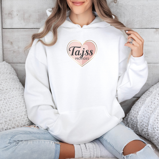 Person wearing a white hoodie with a heart-shaped logo and text, sitting on a wooden floor.